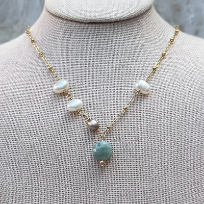 A necklace with a focus on hand-wired freshwater pearls and a Burma Jade faceted stone, with a 14K gold filled finish.