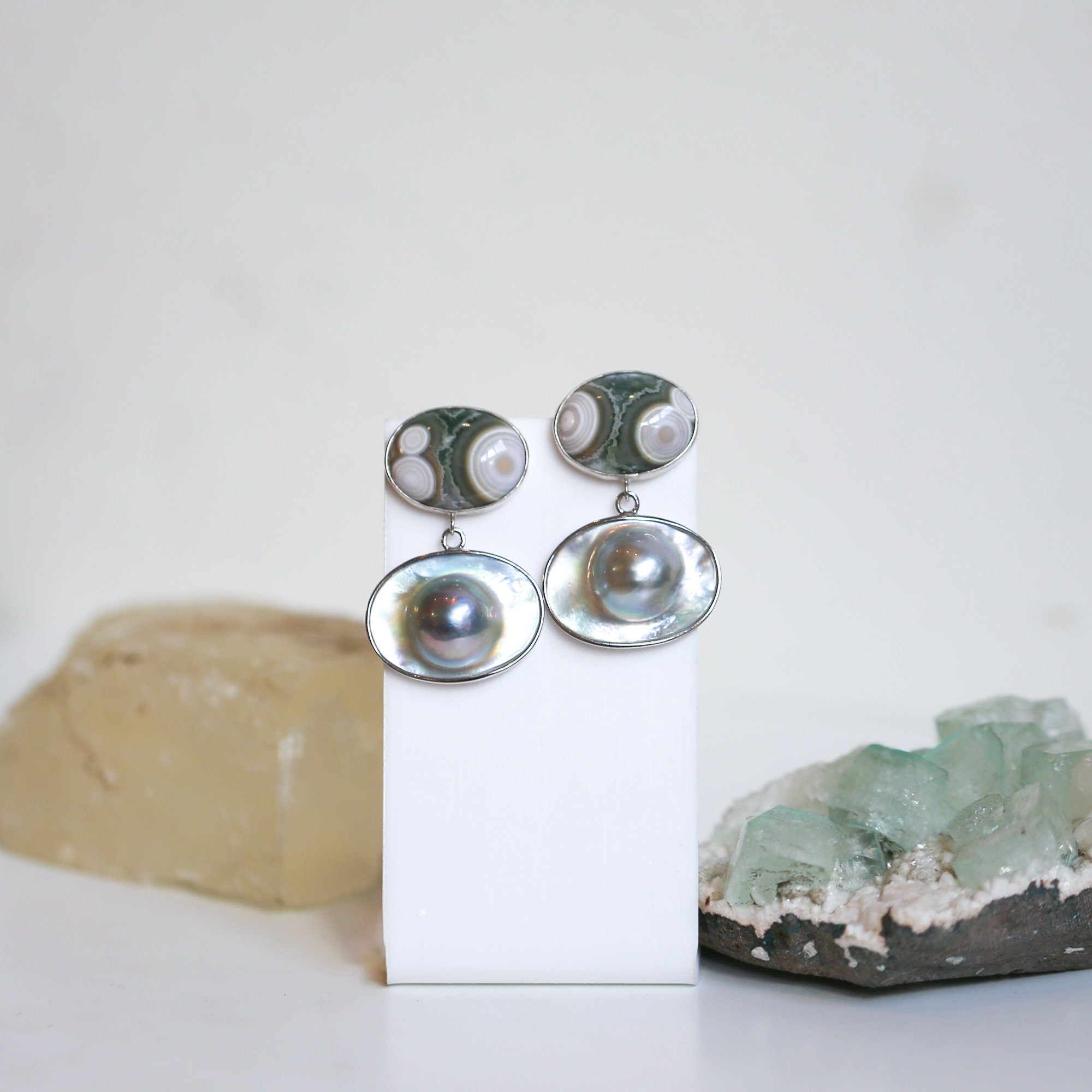 May include: A pair of silver earrings with a green and white agate stone and a pearl drop.