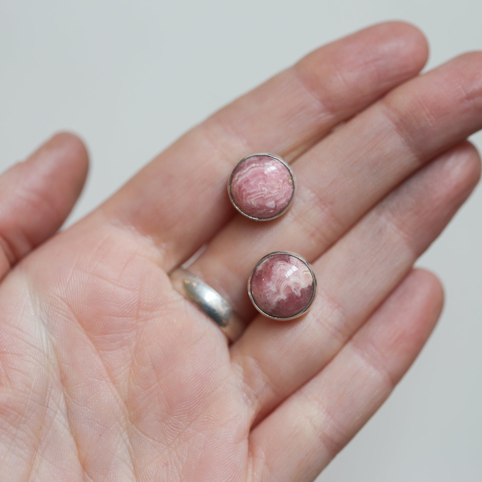 May include: A pair of silver stud earrings with pink and white round cabochon stones