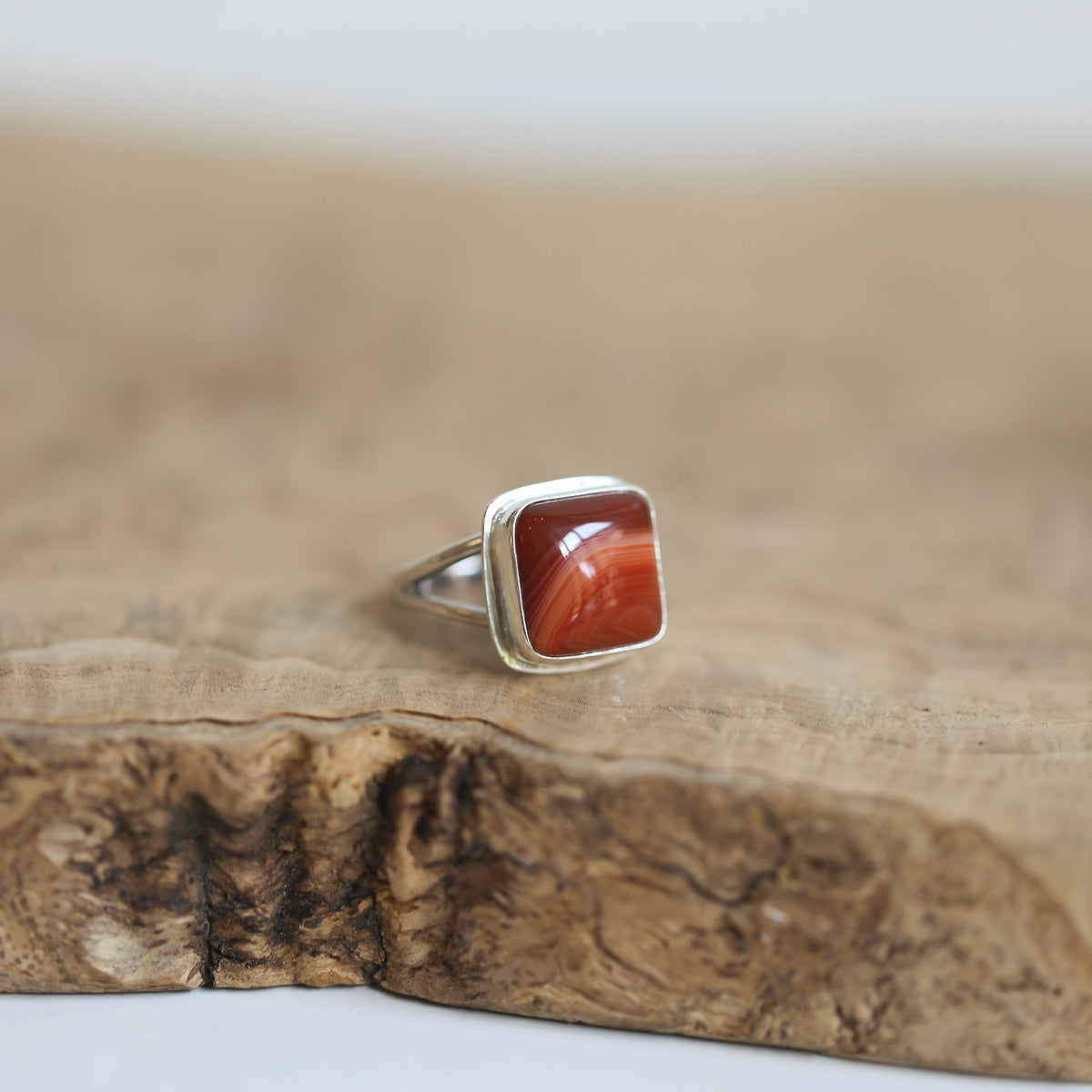 May include: A silver ring with a square shaped red agate stone