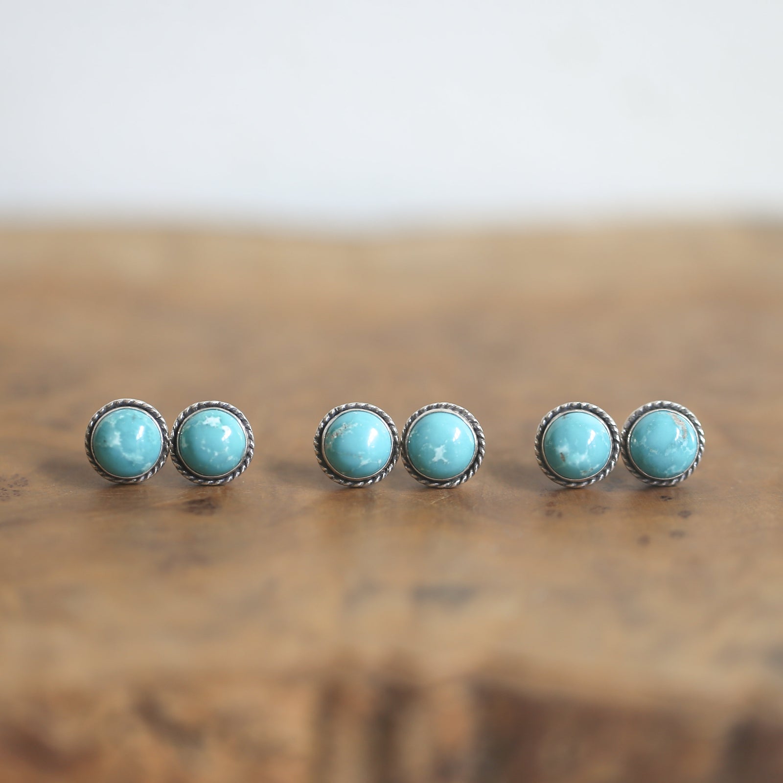 May include: Three pairs of silver stud earrings with turquoise stones. The stones are round and have a light blue color.