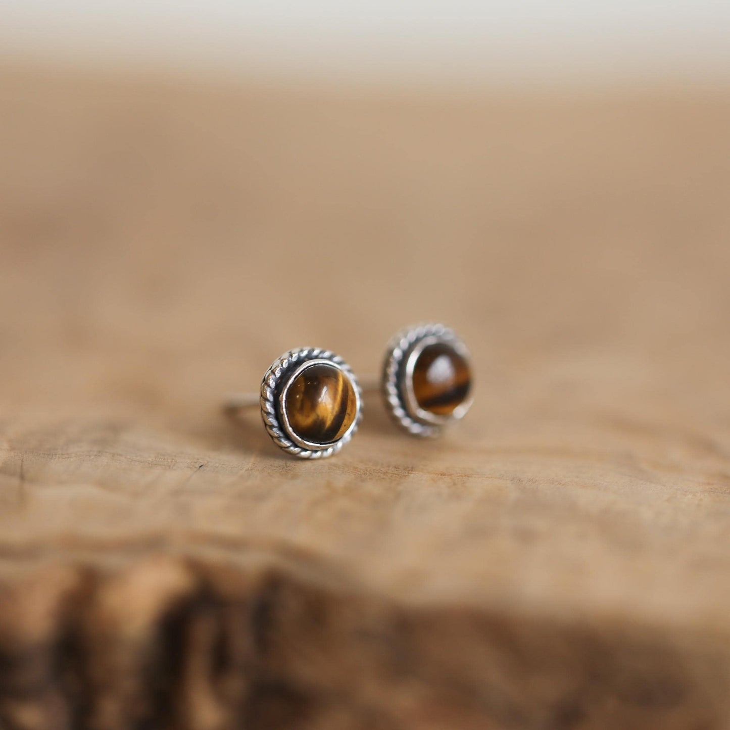 May include: A pair of silver stud earrings with round tiger's eye gemstones