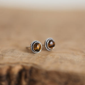 May include: A pair of silver stud earrings with round tiger's eye gemstones