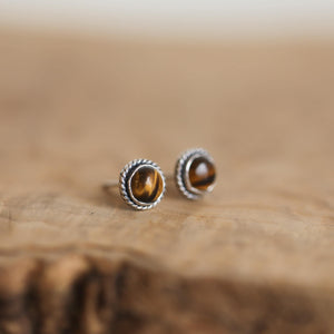 May include: A pair of silver stud earrings with round tiger's eye gemstones