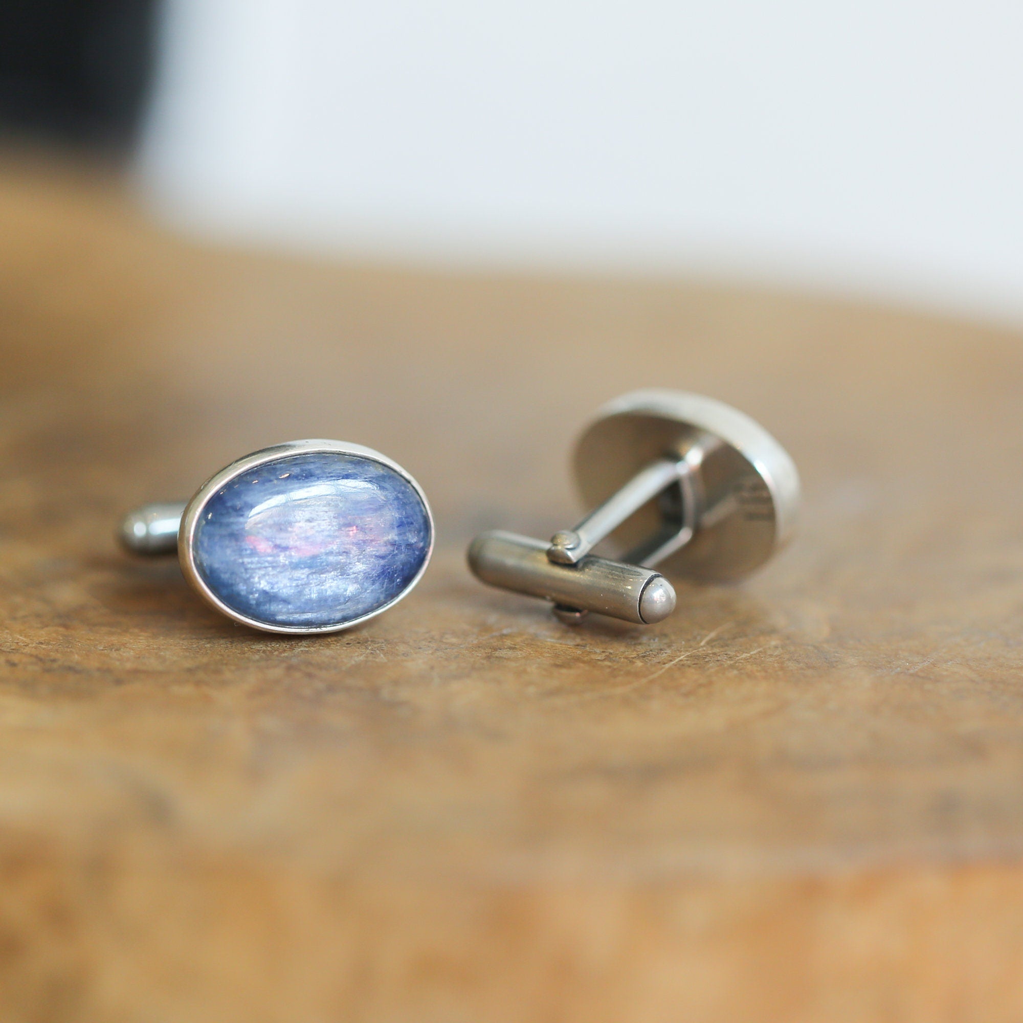 May include: A pair of silver cufflinks with oval blue gemstone insets.