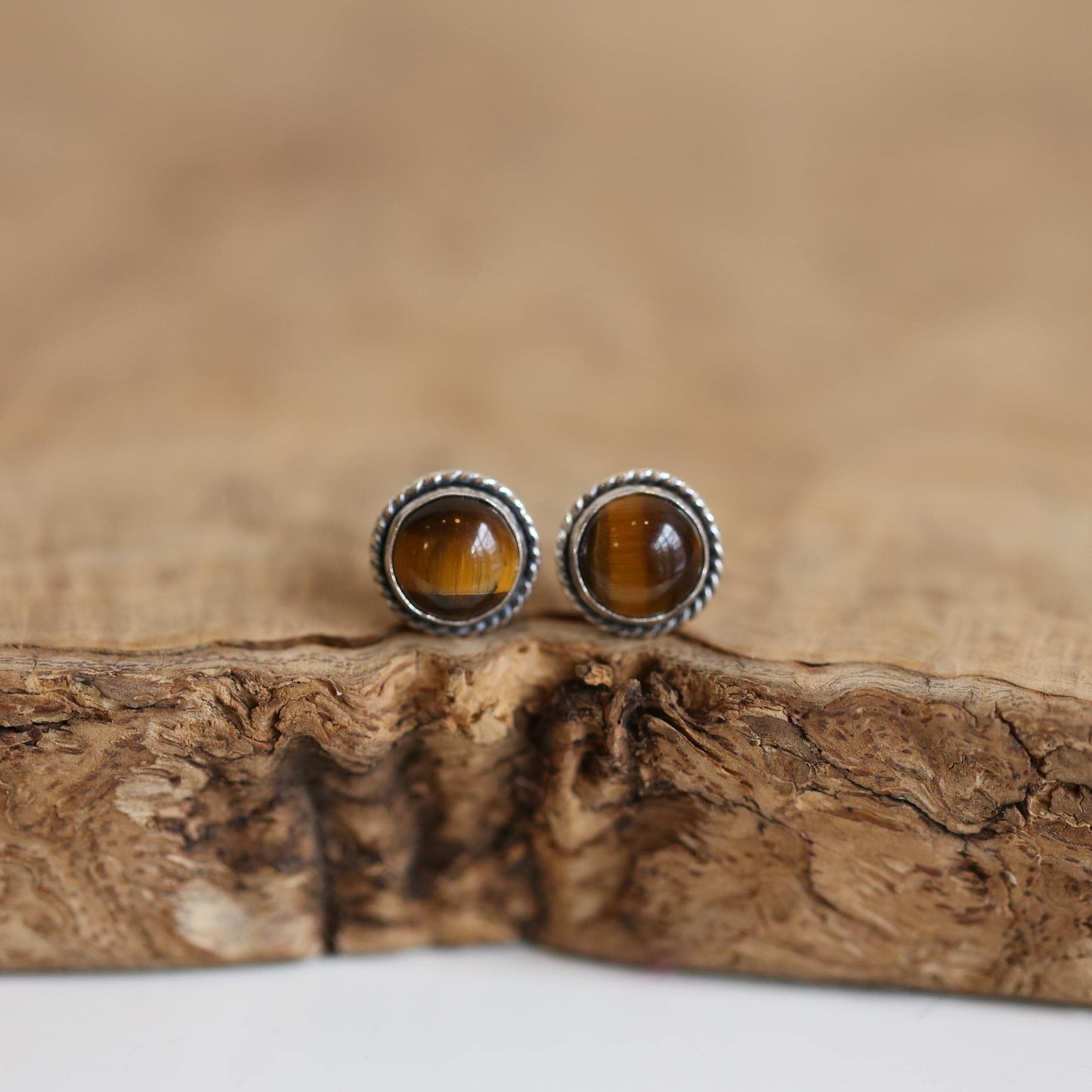 May include: Two silver stud earrings with brown tiger's eye gemstones