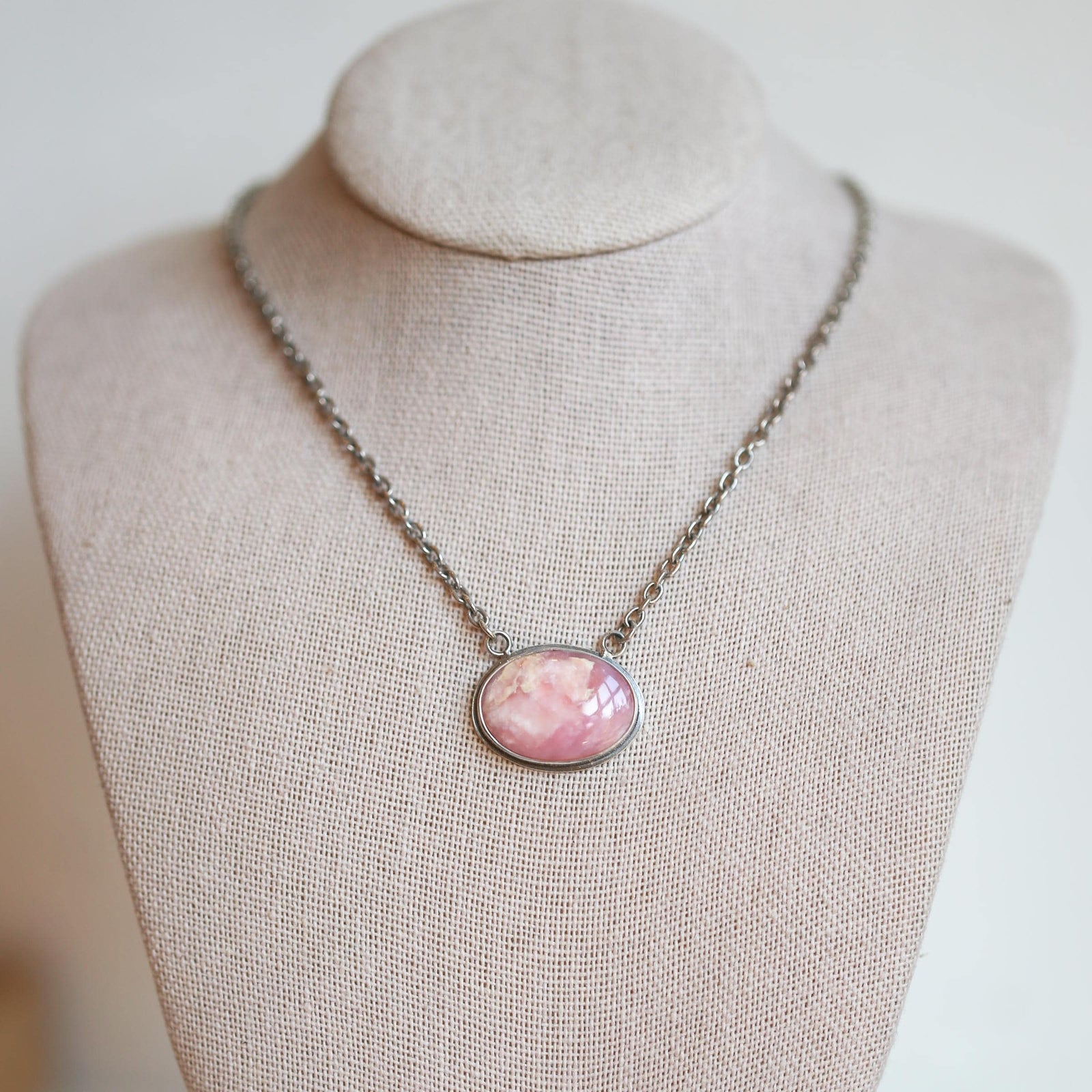 May include: A silver chain necklace with a pink oval pendant
