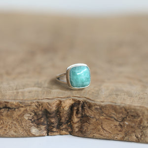 May include: A silver ring with a square shaped turquoise gemstone