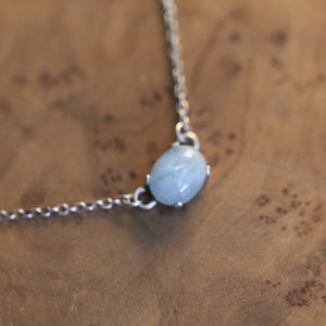 May include: A silver chain necklace with a light blue oval gemstone pendant.