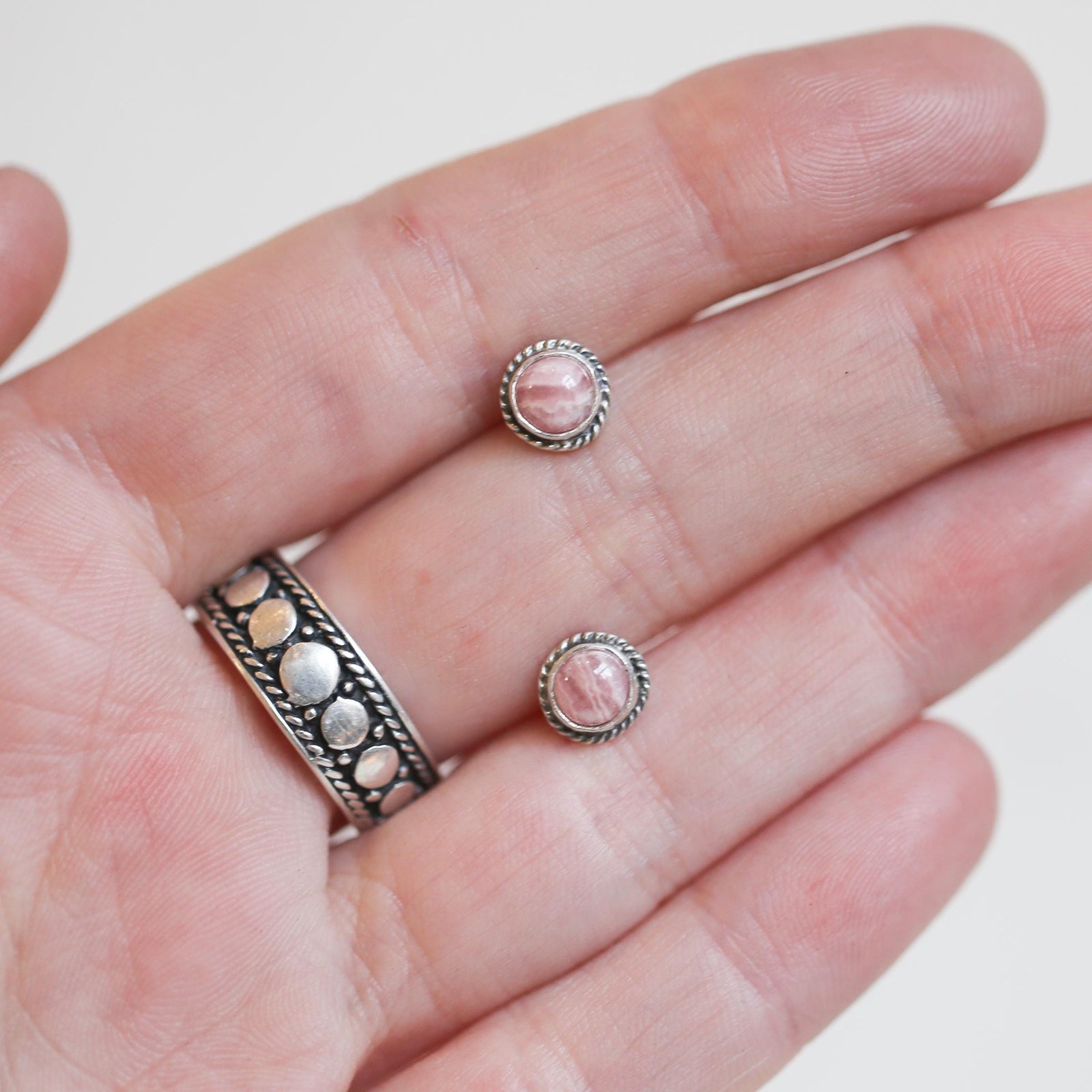May include: A pair of silver stud earrings with pink and white striped stone accents.