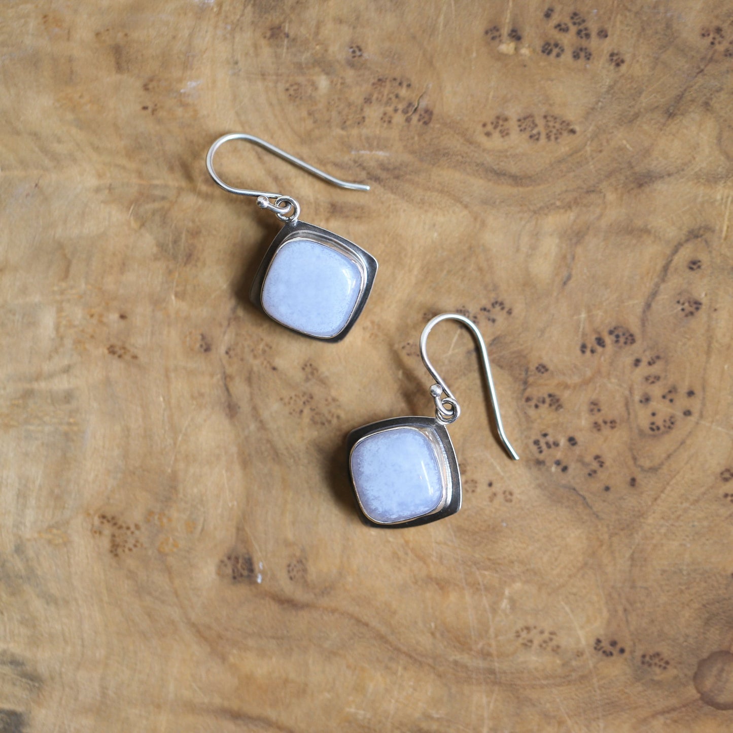 May include: A pair of silver earrings with square-shaped light blue gemstone accents.