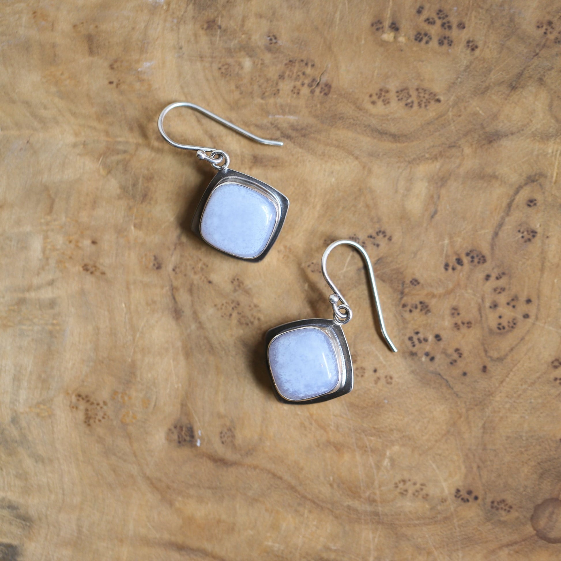 May include: A pair of silver earrings with square-shaped light blue gemstone accents.