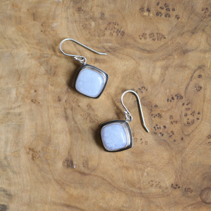 May include: A pair of silver earrings with square-shaped light blue gemstone accents.