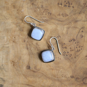 May include: A pair of silver earrings with square-shaped light blue gemstone accents.