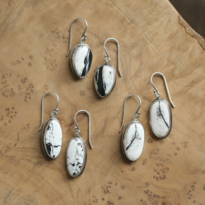 May include: Five pairs of silver dangle earrings with oval-shaped white and black stones. The stones have a natural, marbled pattern.