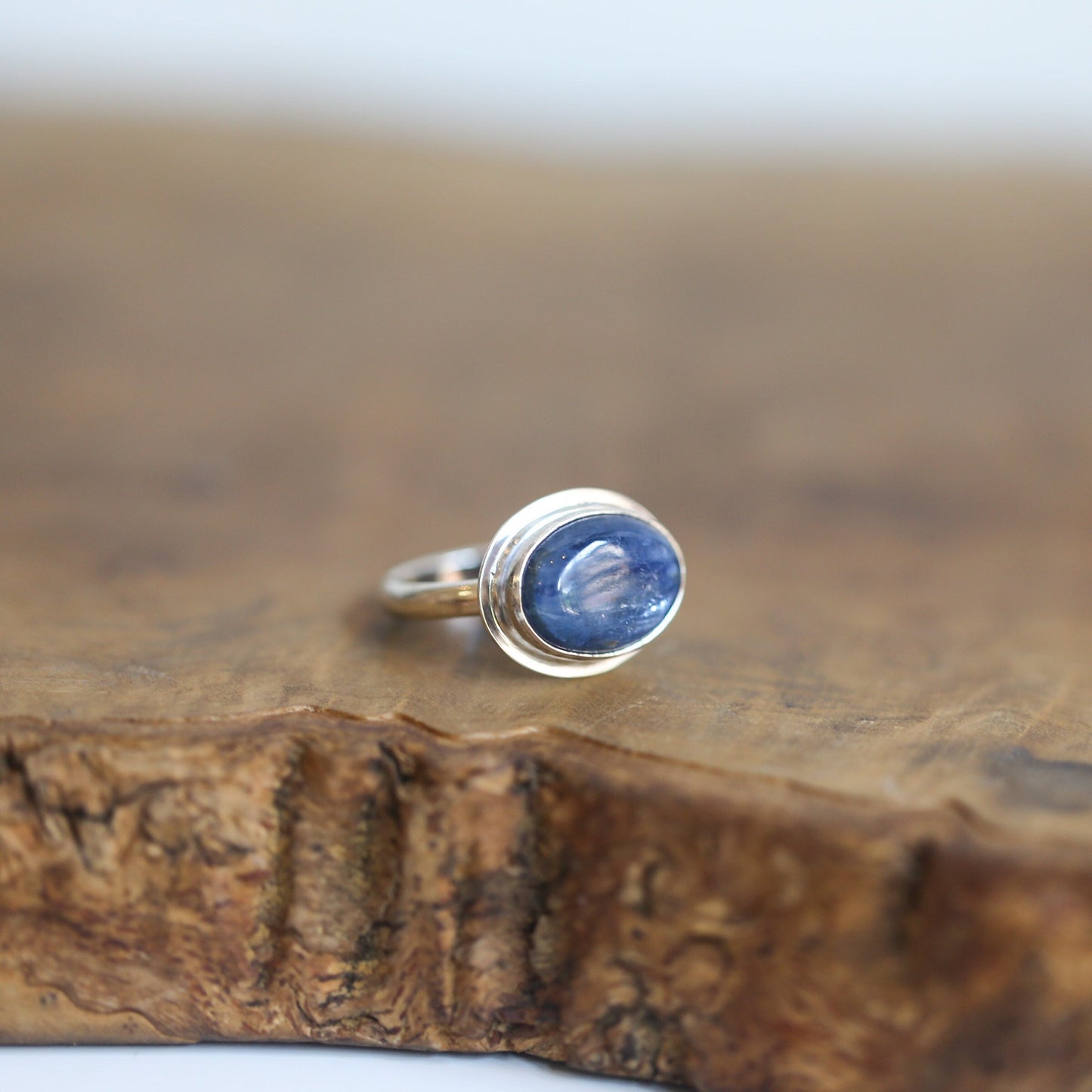 May include: A silver ring with a blue oval gemstone set in a bezel setting.
