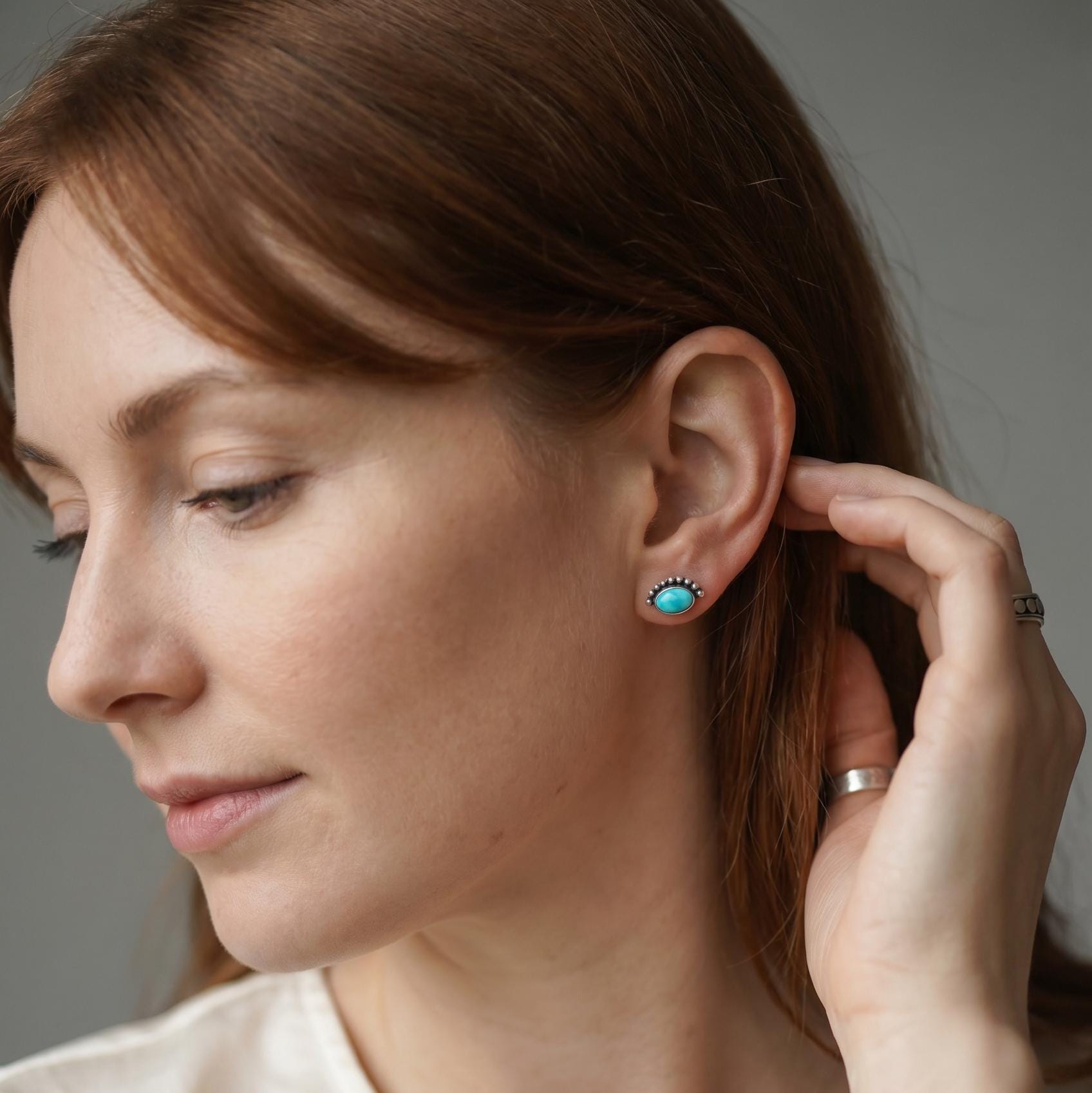 Woman wearing turquoise earrings with a neutral background