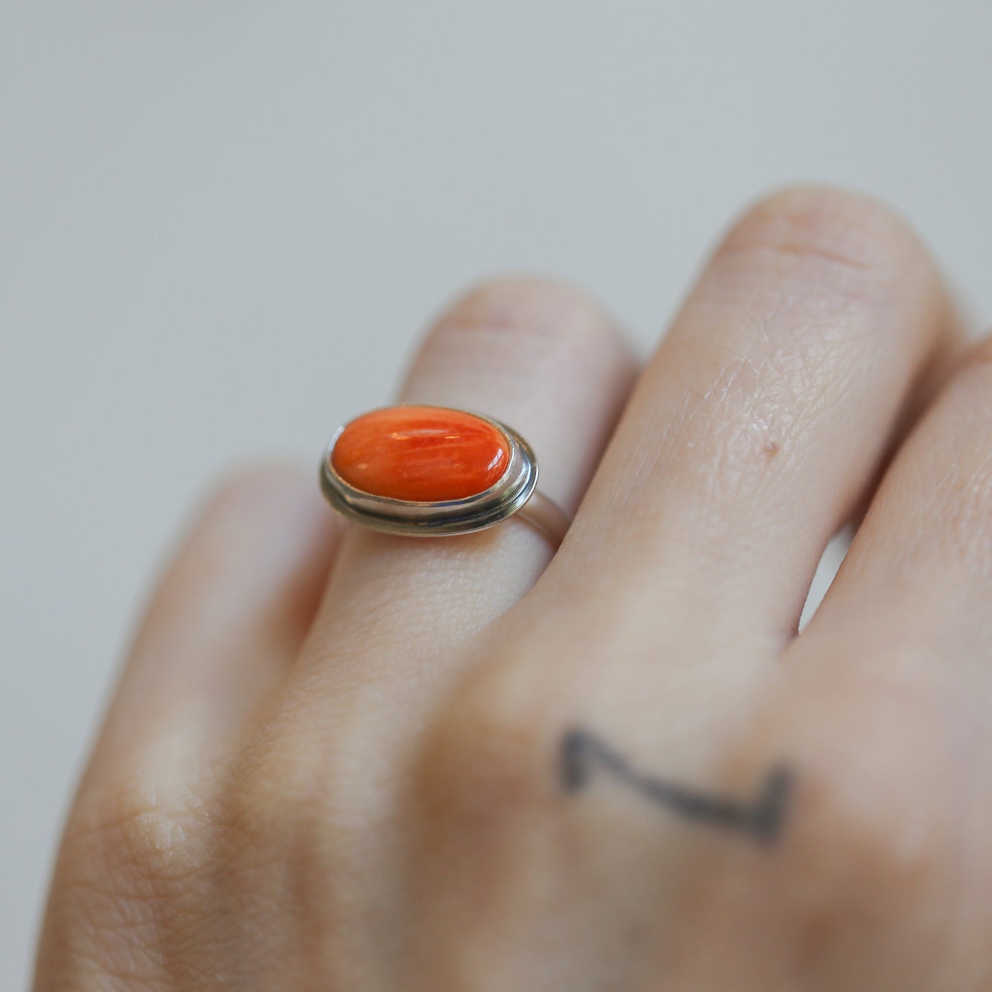 May include: A silver ring with an oval-shaped orange gemstone set in a silver bezel.